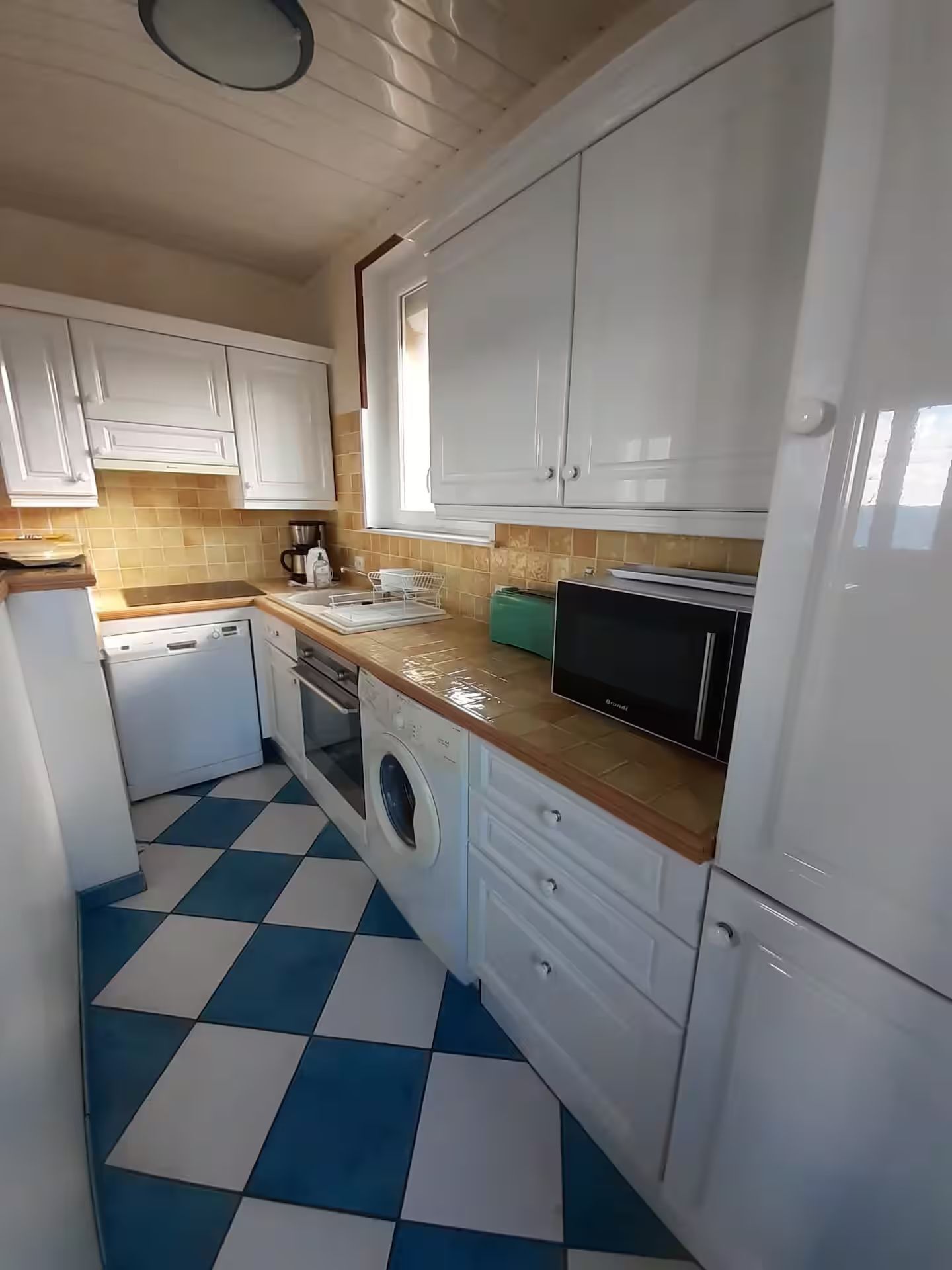 Une cuisine avec des armoires blanches et un sol Ă carreaux bleus et blancs