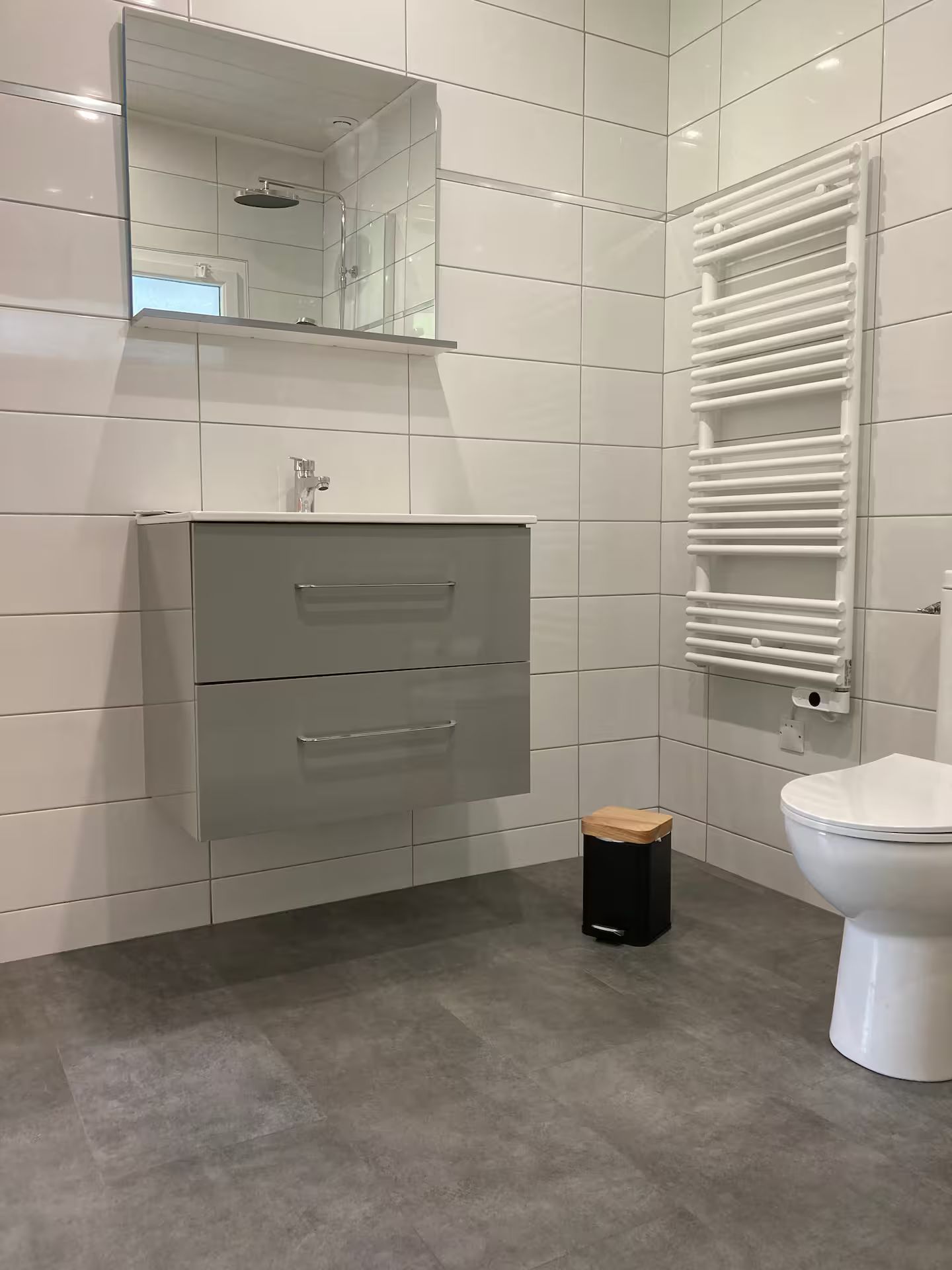Une salle de bain avec WC, lavabo, miroir et porte-serviettes.