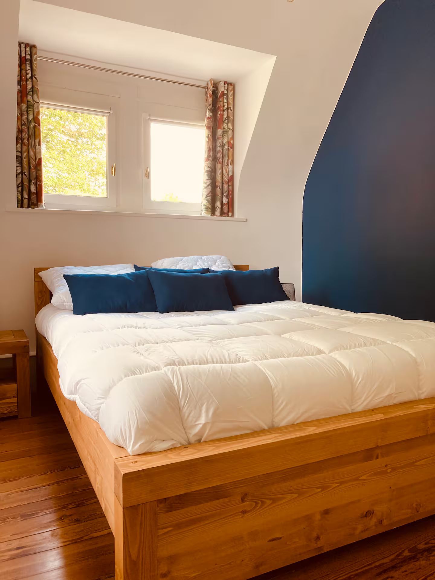 Un lit avec des draps blancs et des oreillers bleus dans une chambre avec un mur bleu.