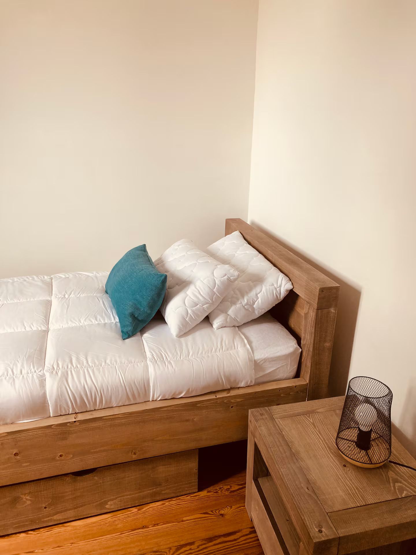 Une chambre avec un lit, une table de chevet et une lampe.