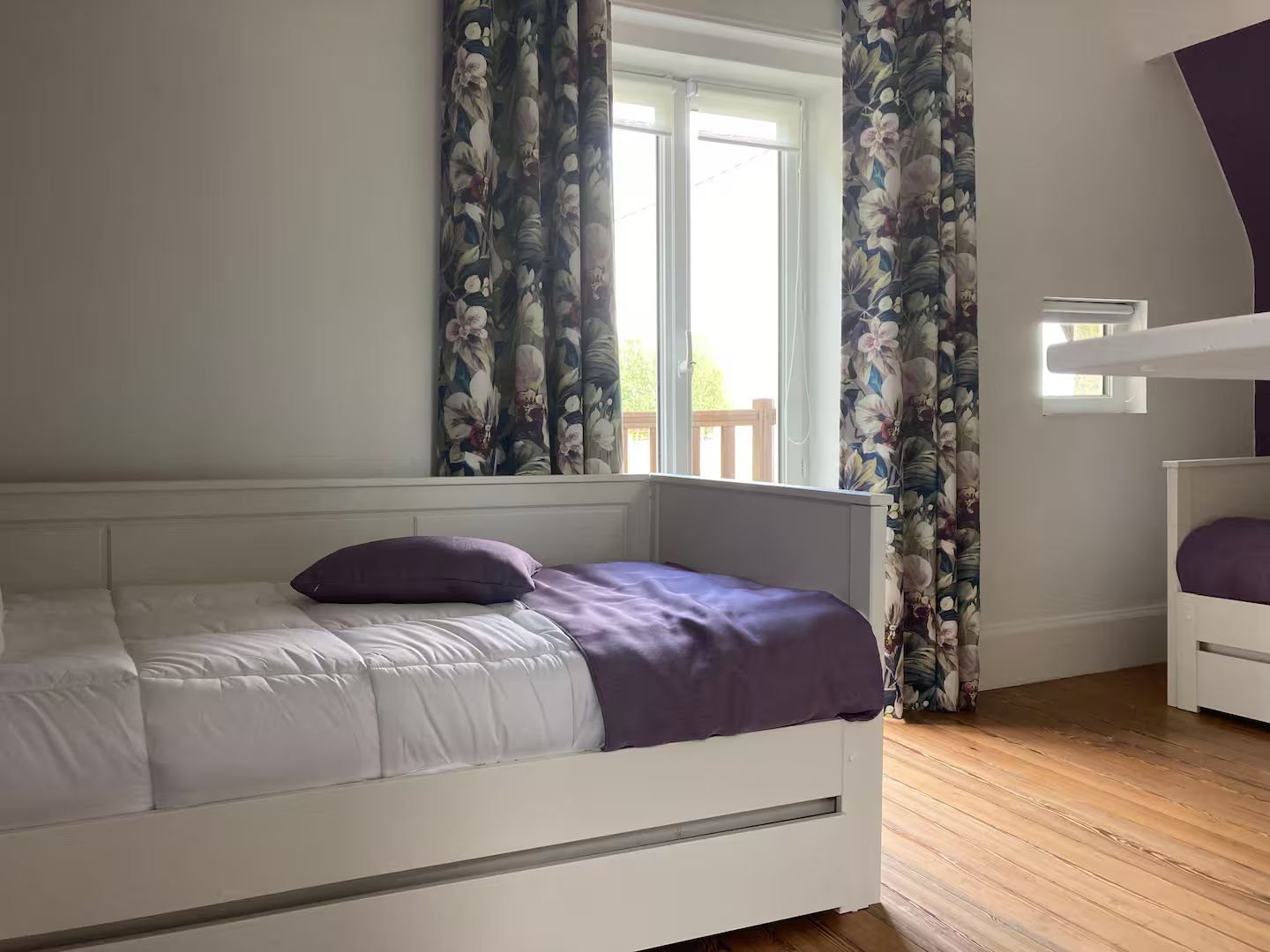 Une chambre avec deux lits et une fenêtre avec des rideaux violets.