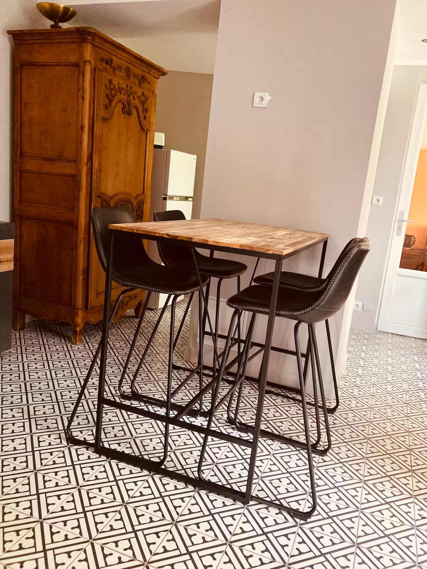 Une table et des chaises sont posées sur un sol carrelé dans un salon.