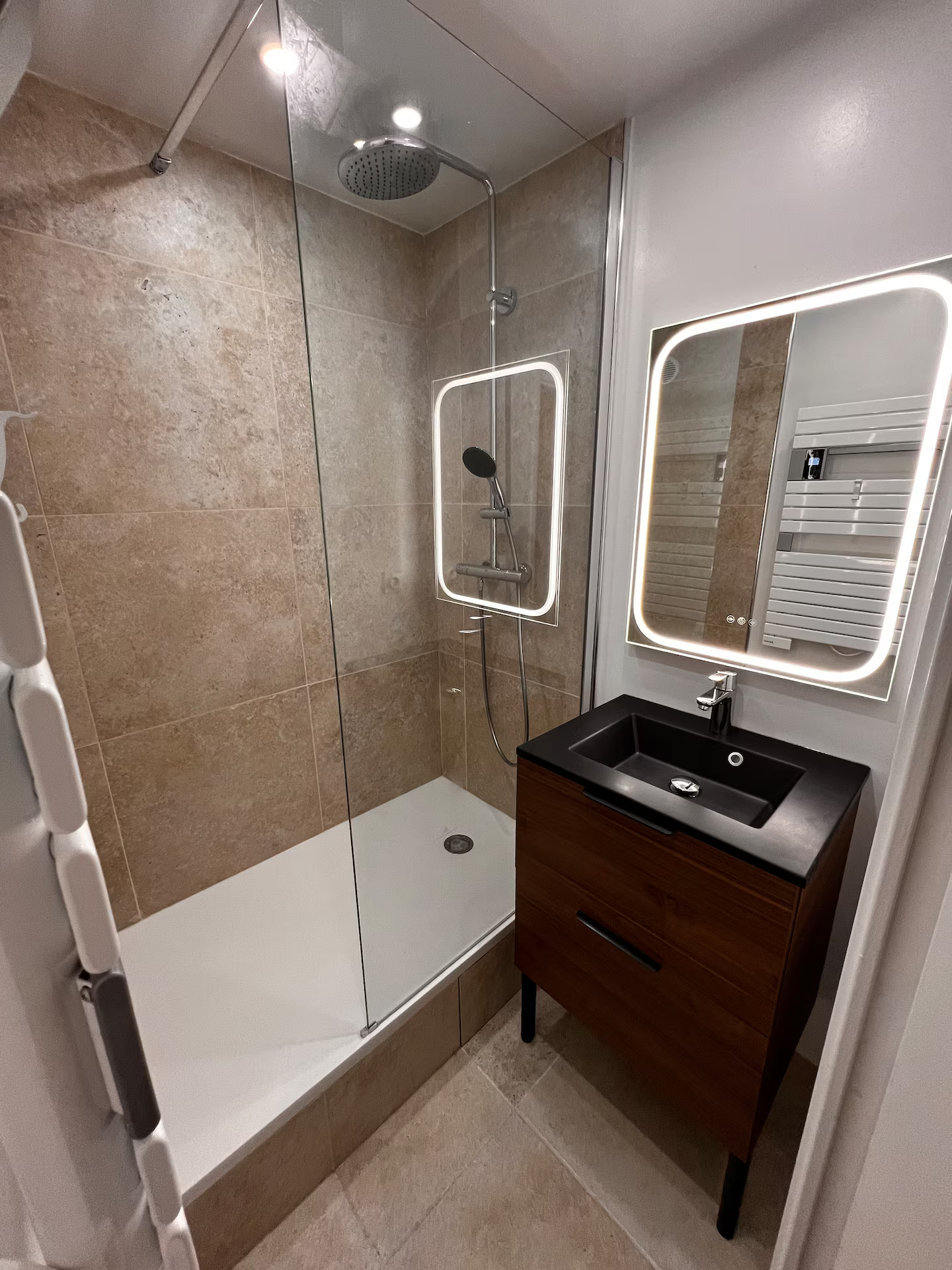 Une salle de bain avec douche, lavabo et miroir.