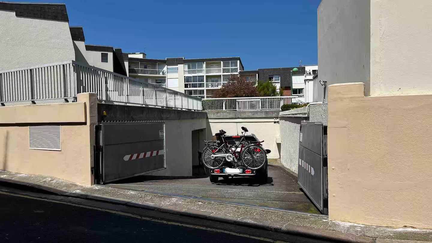 Une voiture est garée dans un garage avec des vélos à l'arrière.
