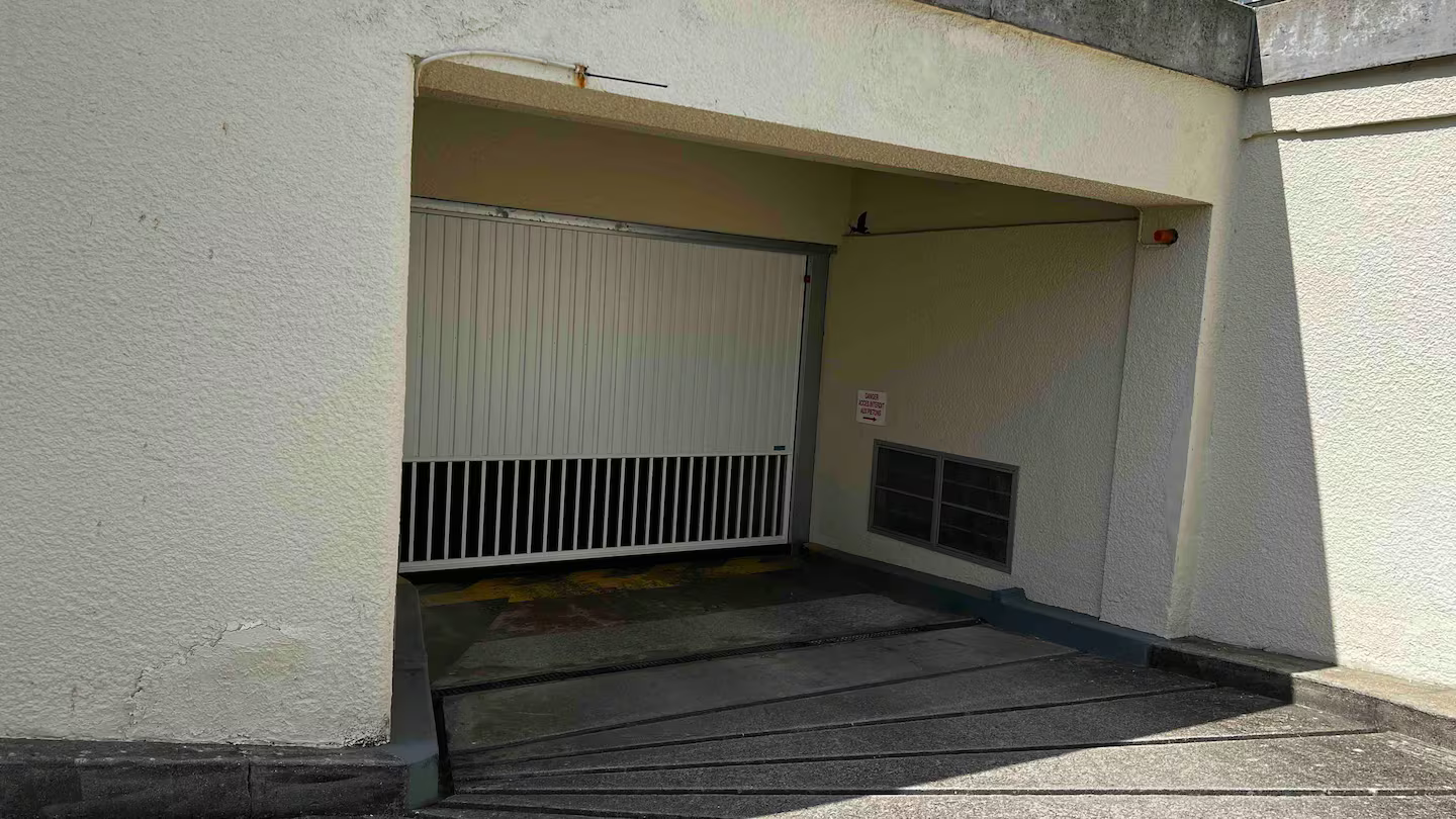 Un garage avec un portail blanc et un sol en béton.