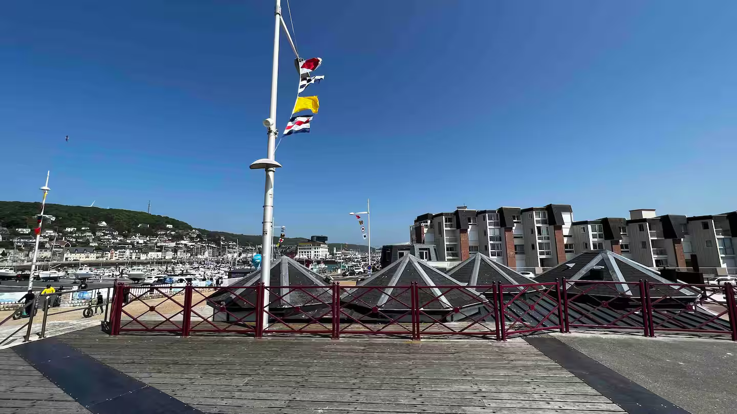 Un mât avec des drapeaux flottant au vent devant une ville.