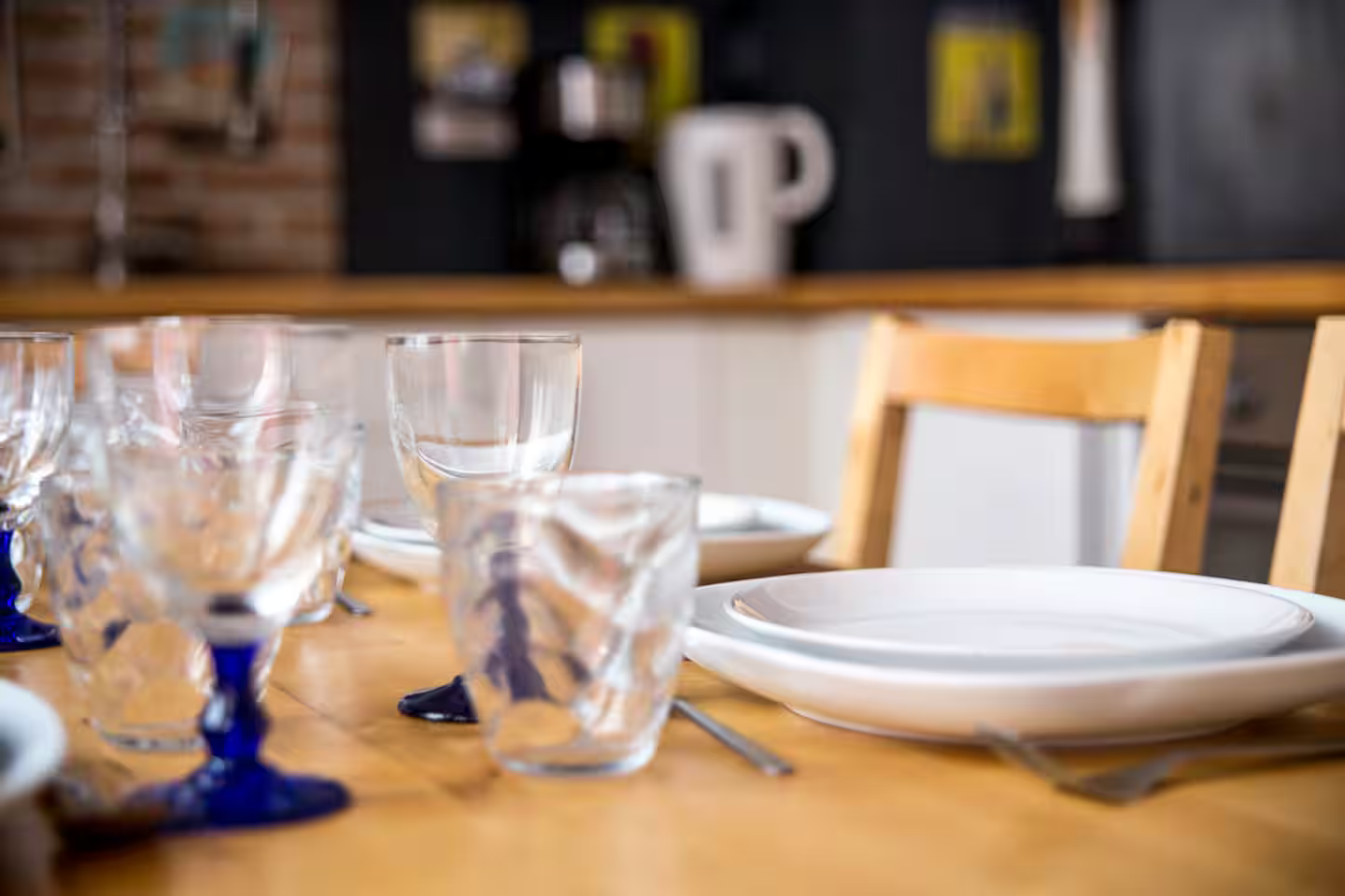 Une table en bois avec des assiettes, des verres et des couverts dessus.