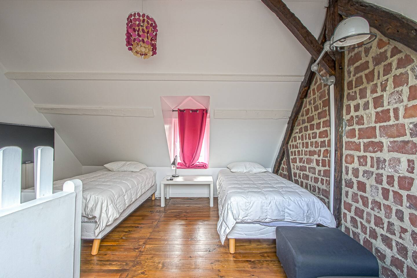 Une chambre avec deux lits et un mur en briques.