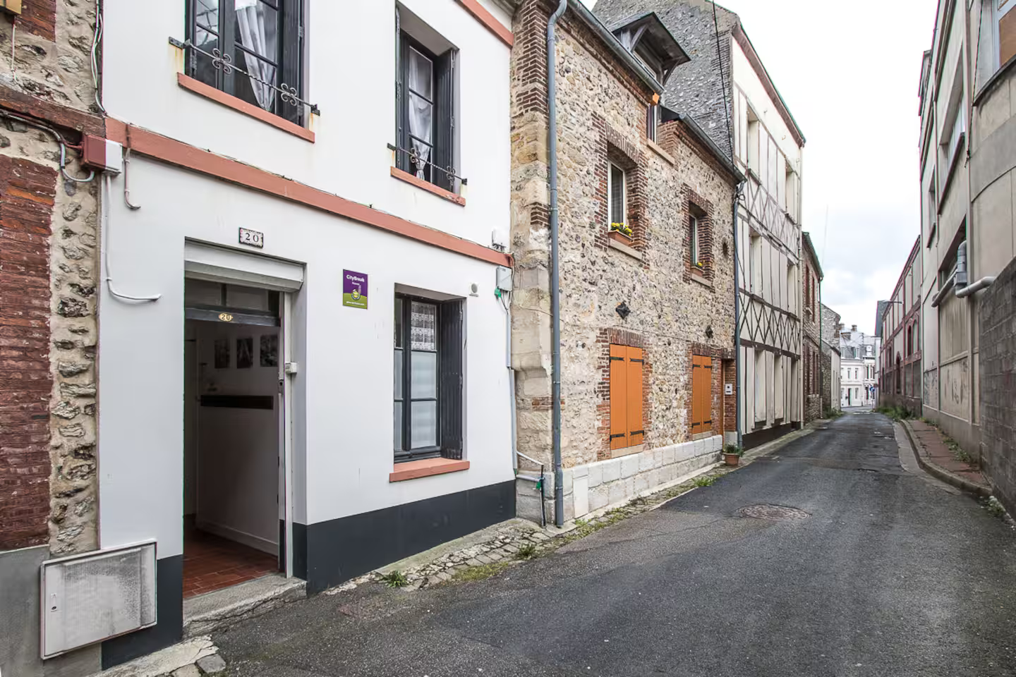 Une ruelle étroite entre deux bâtiments avec un bâtiment blanc au milieu.