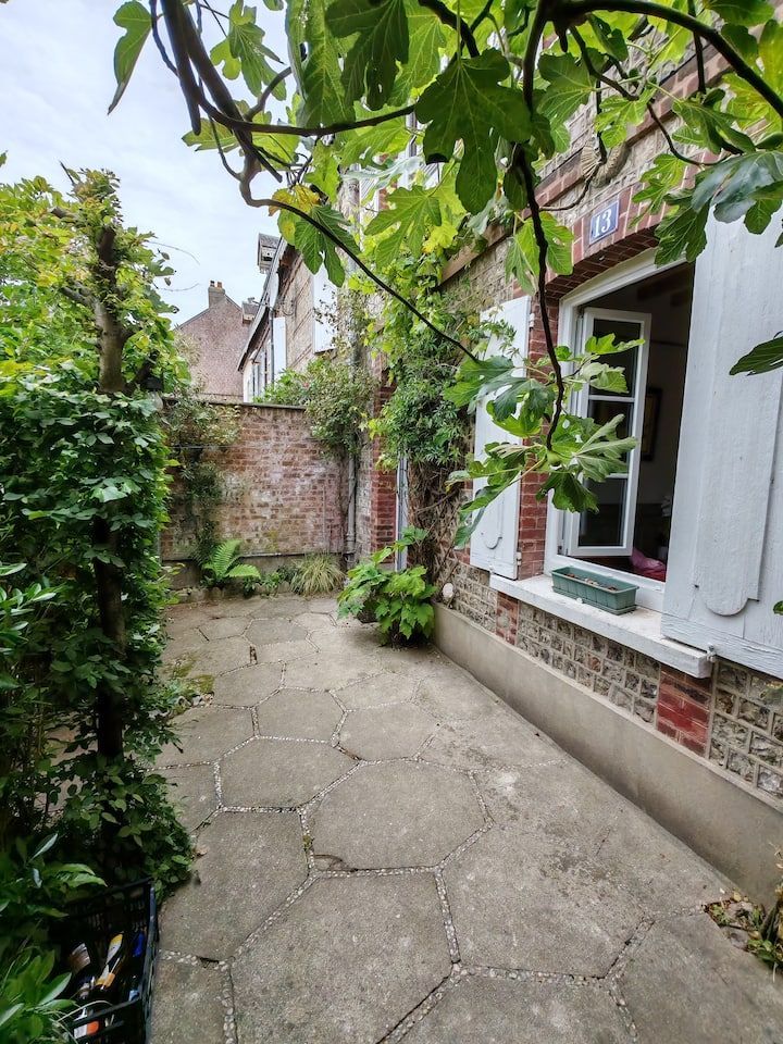 Petit patio en briques avec végétation et fenêtre.