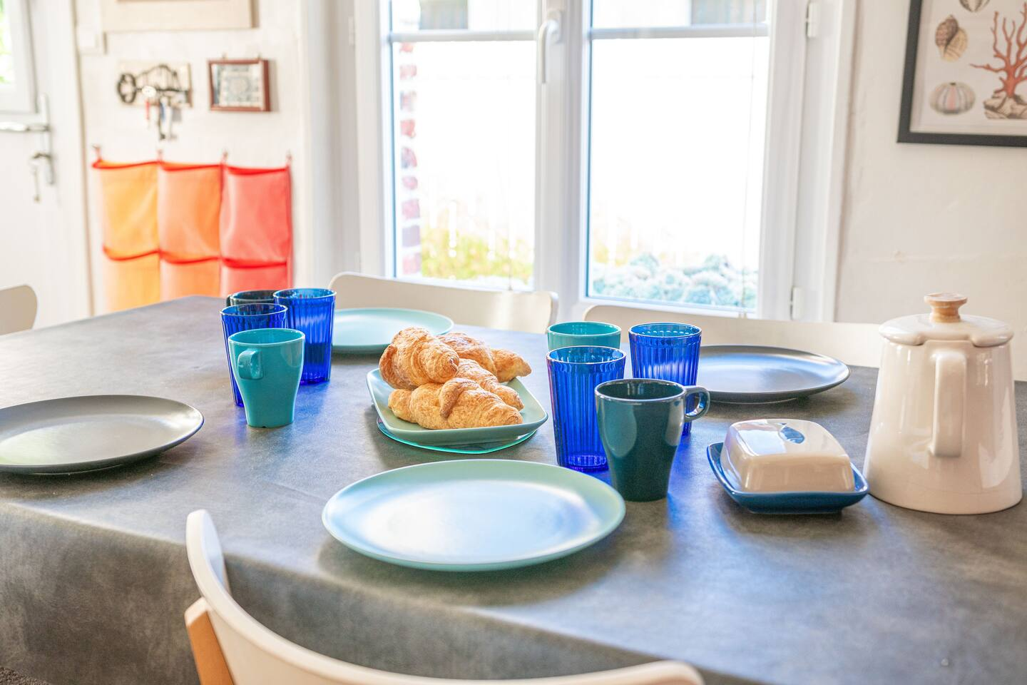 Une table de salle à manger avec des assiettes, des tasses et des croissants dessus.