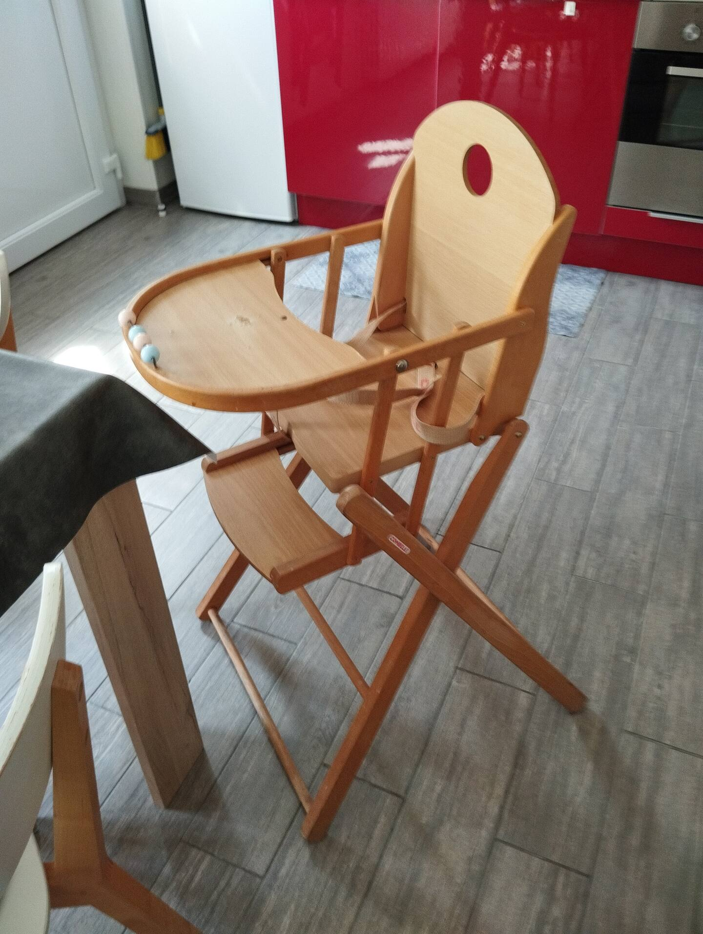 Une chaise haute en bois est posée dans une cuisine à côté d'une table