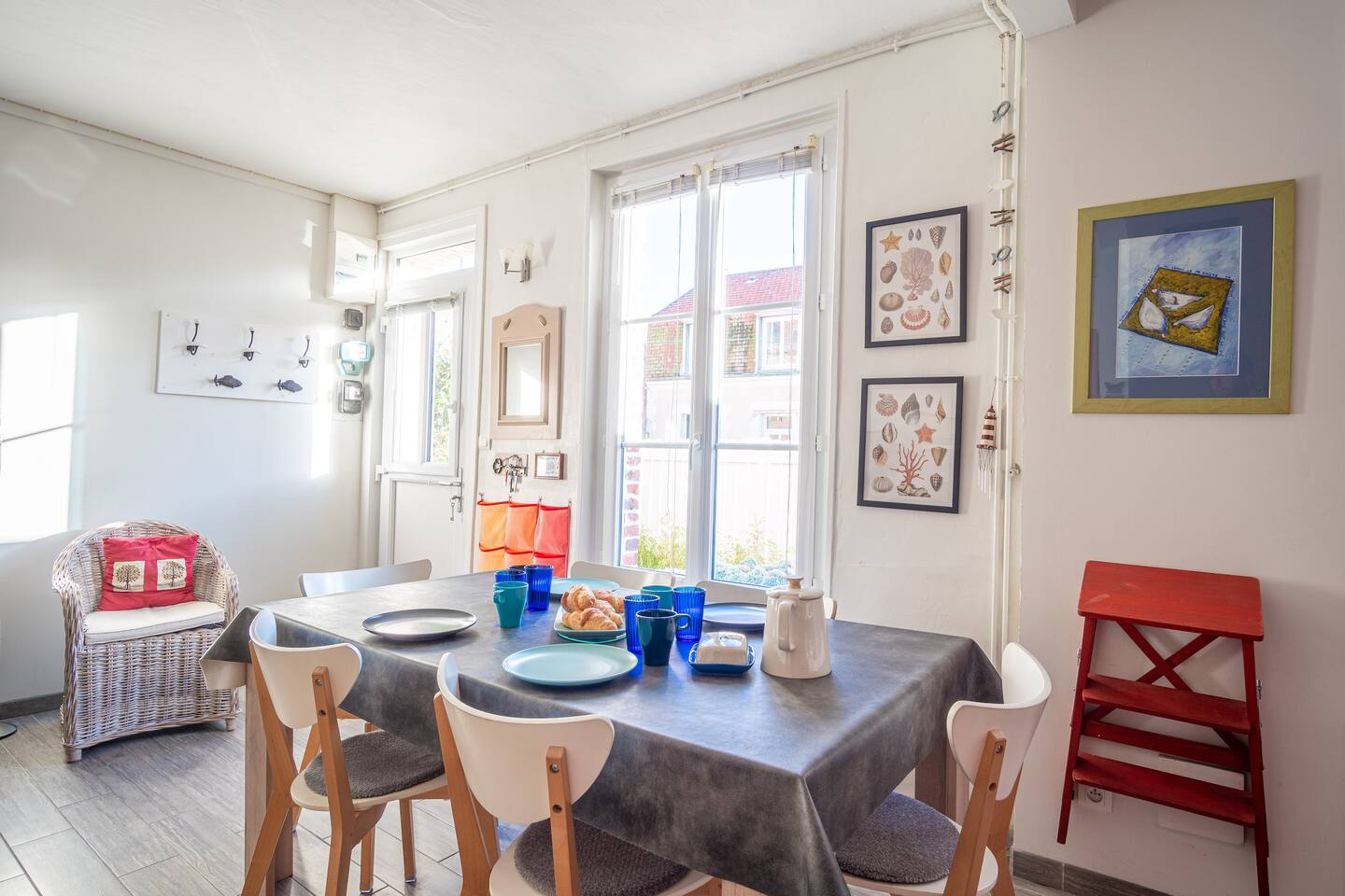 Une salle à manger avec une table et des chaises et un tabouret rouge.