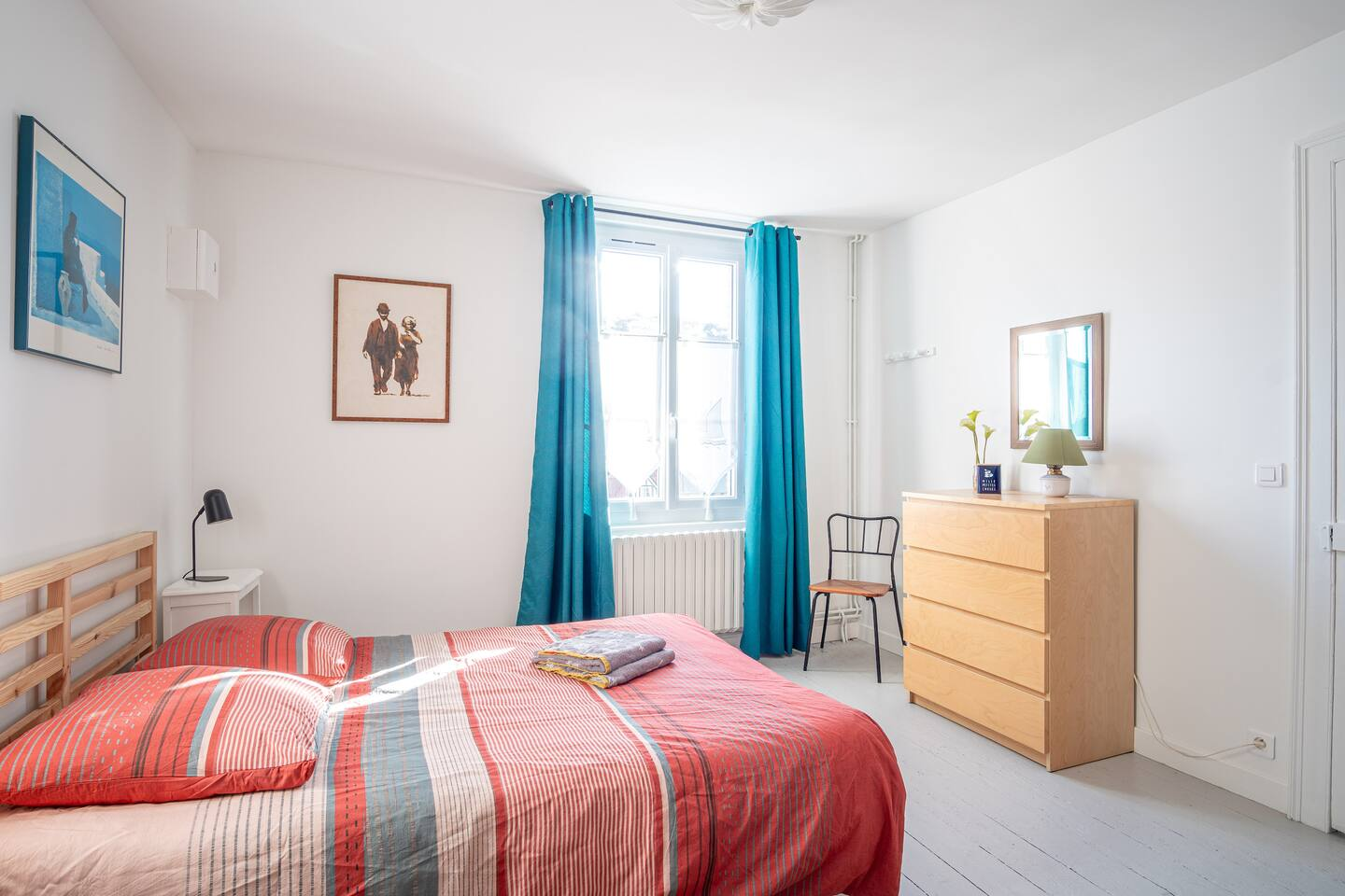 Une chambre avec un lit, une commode, une chaise et une fenêtre.