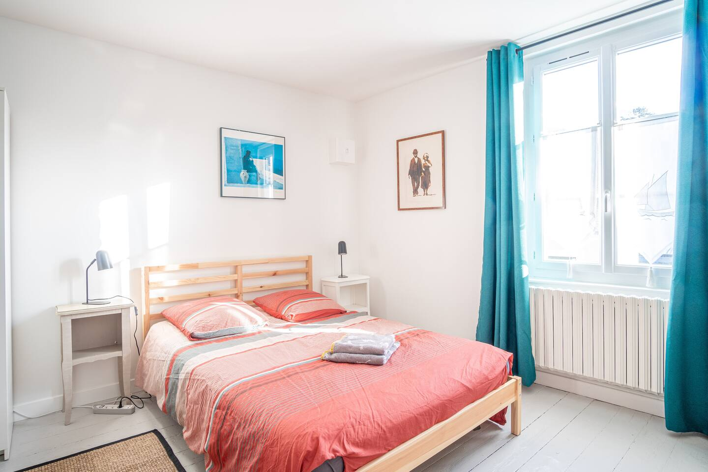 Une chambre avec un lit, une table de chevet, une lampe et une fenêtre.