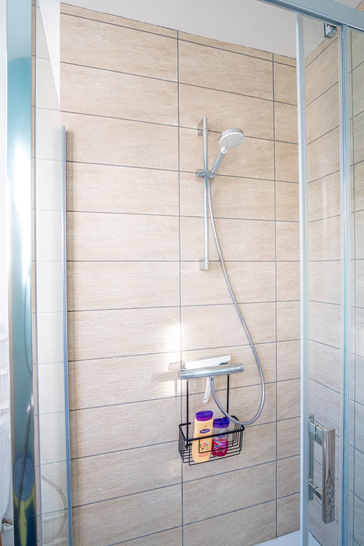 Une douche avec une porte coulissante en verre et une pomme de douche.