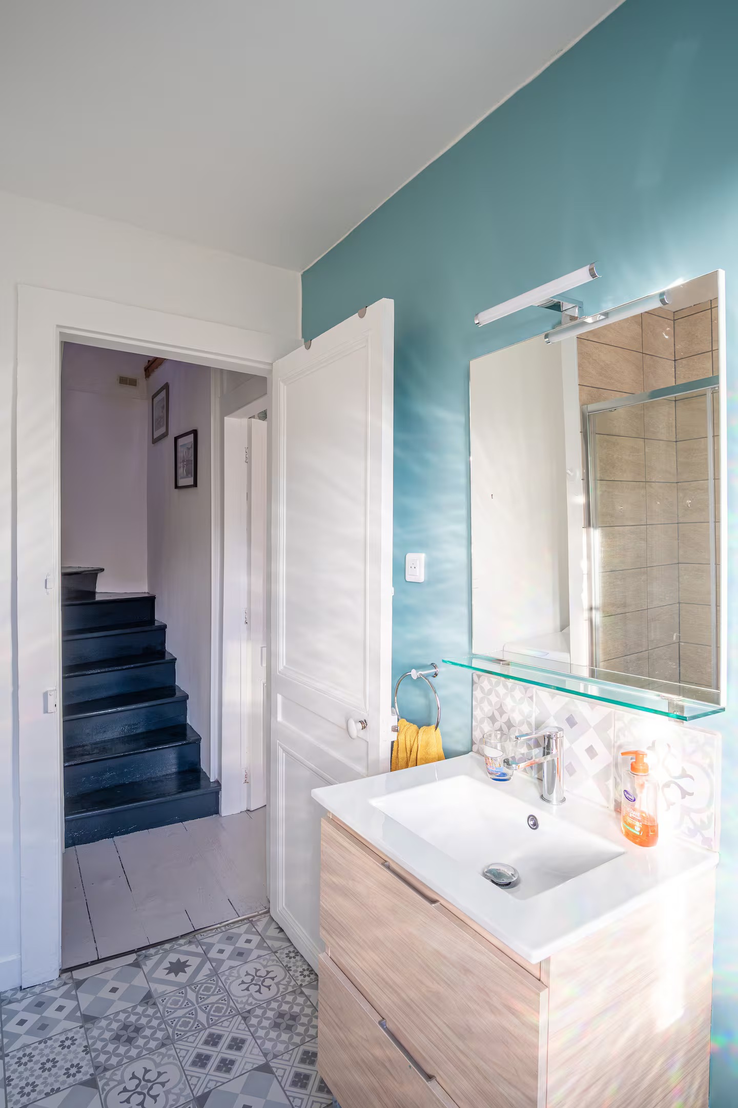 Une salle de bain avec un lavabo, un miroir et un escalier.