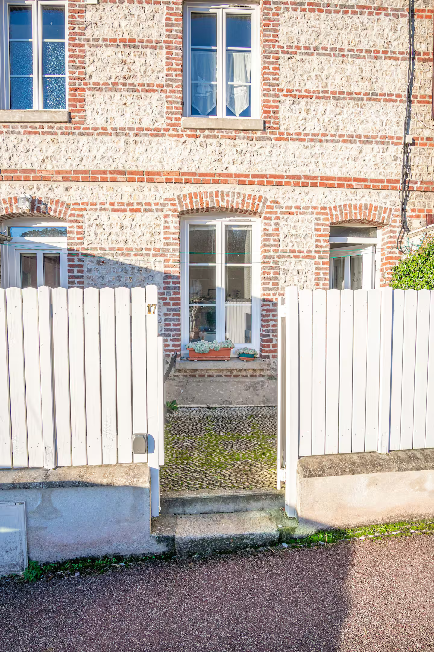 Une clôture en bois blanc se trouve devant un bâtiment en briques.