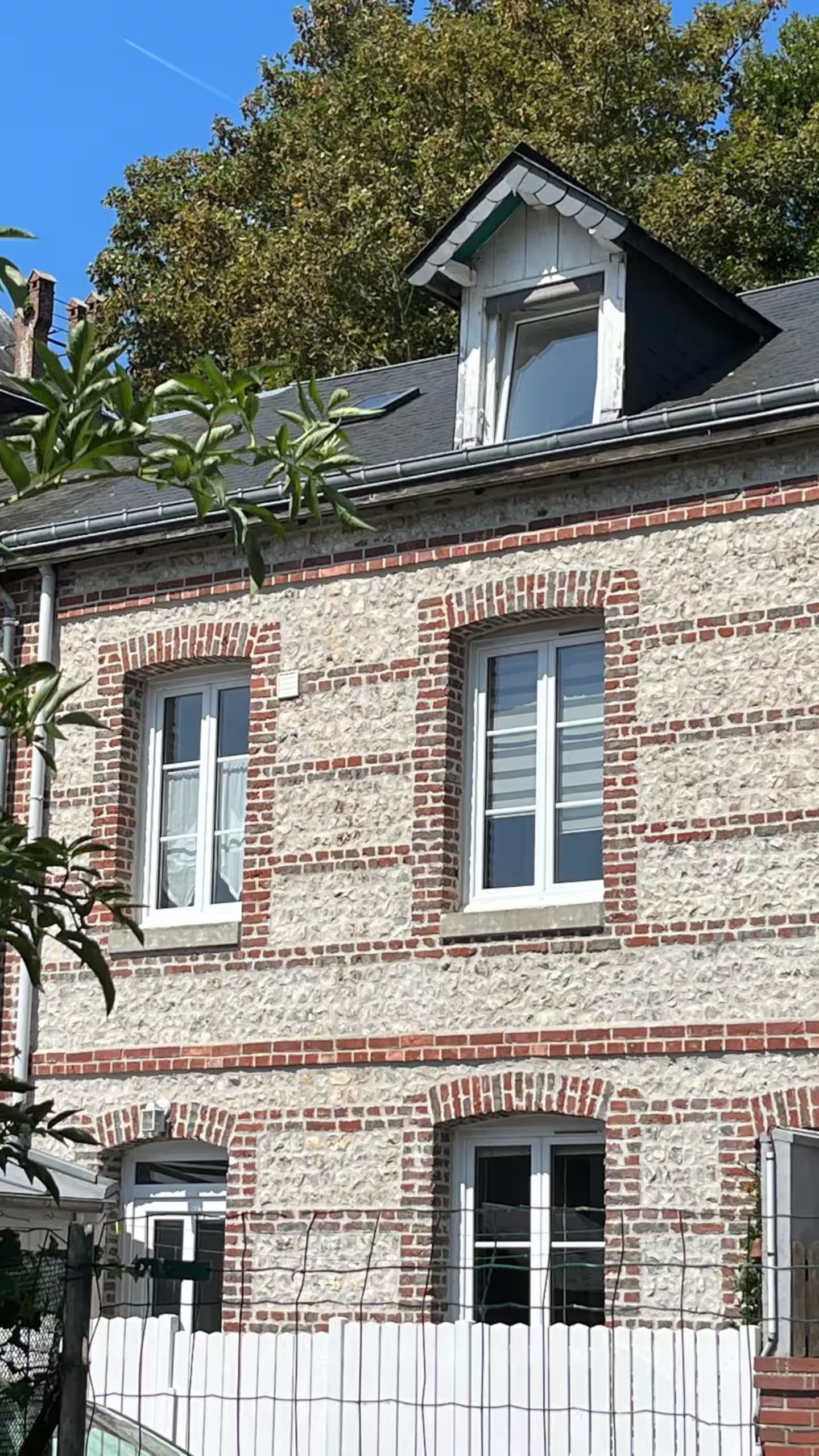 Un bâtiment en briques avec des fenêtres blanches et un toit noir