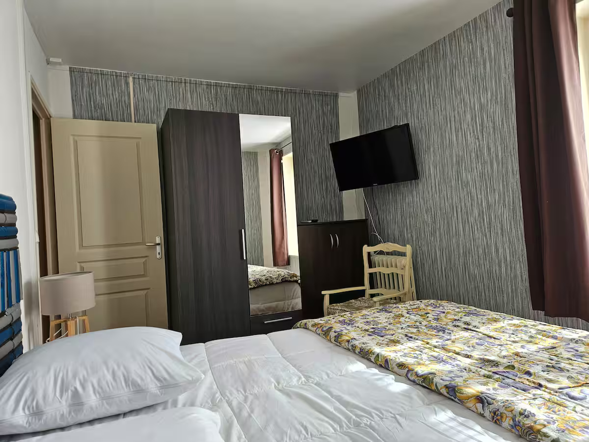 Une chambre avec un lit, une chaise, une télévision et une armoire.
