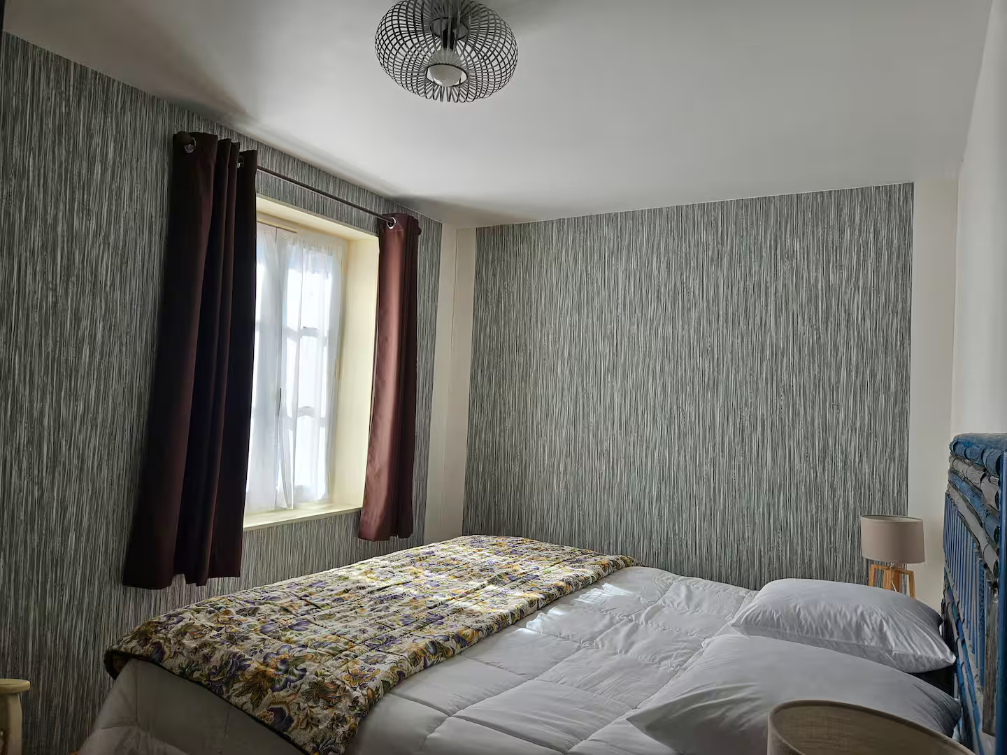 Une chambre avec un lit, des lampes, des rideaux et une fenêtre.