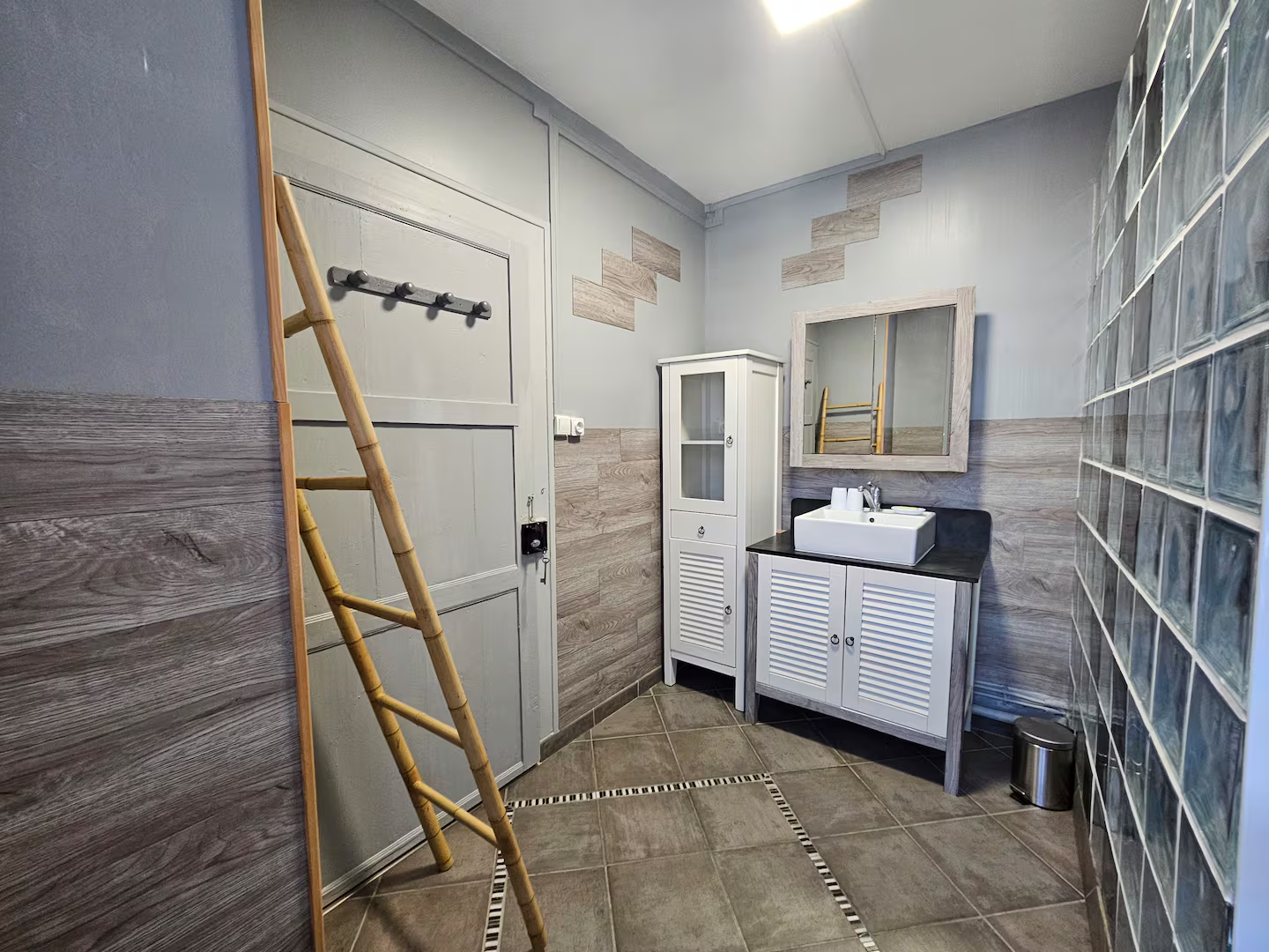 Il y a une échelle dans la salle de bain avec un lavabo et un miroir.