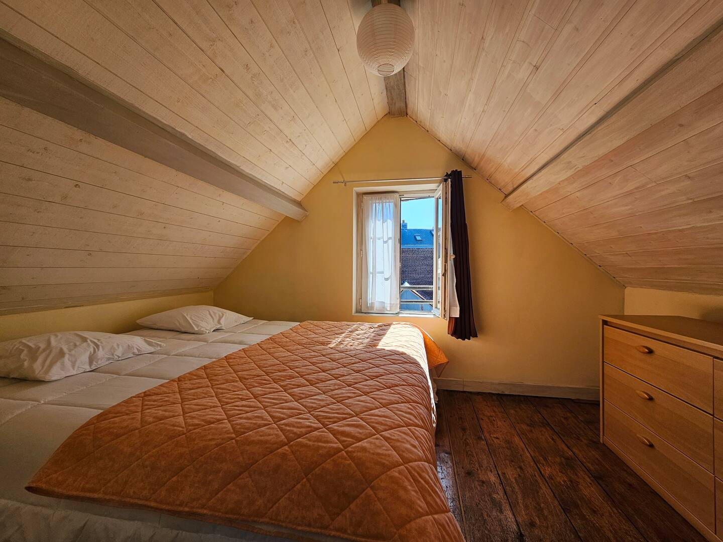 Une chambre mansardée avec deux lits et une fenêtre
