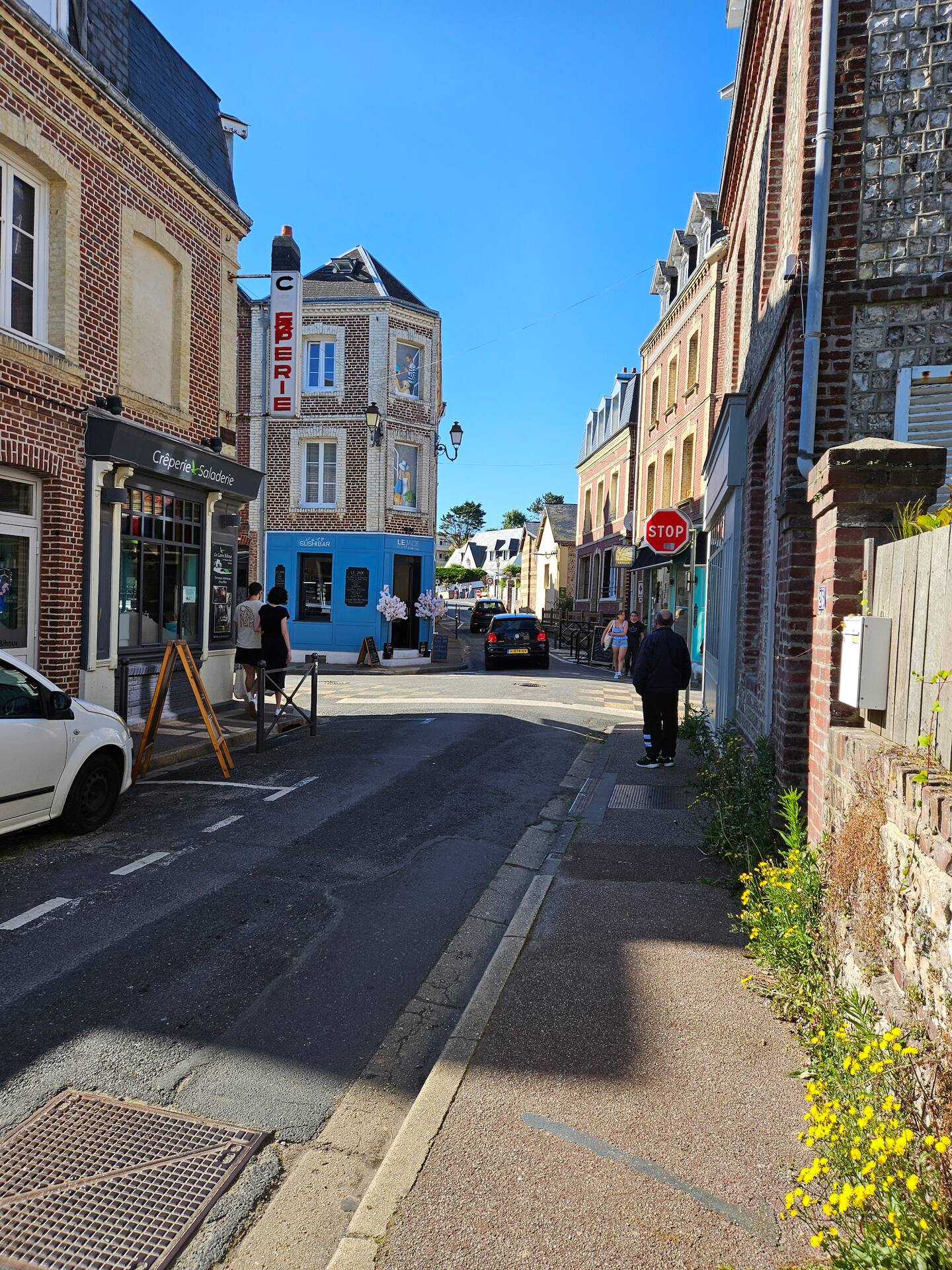 Une rue étroite avec une voiture blanche garée sur le côté.