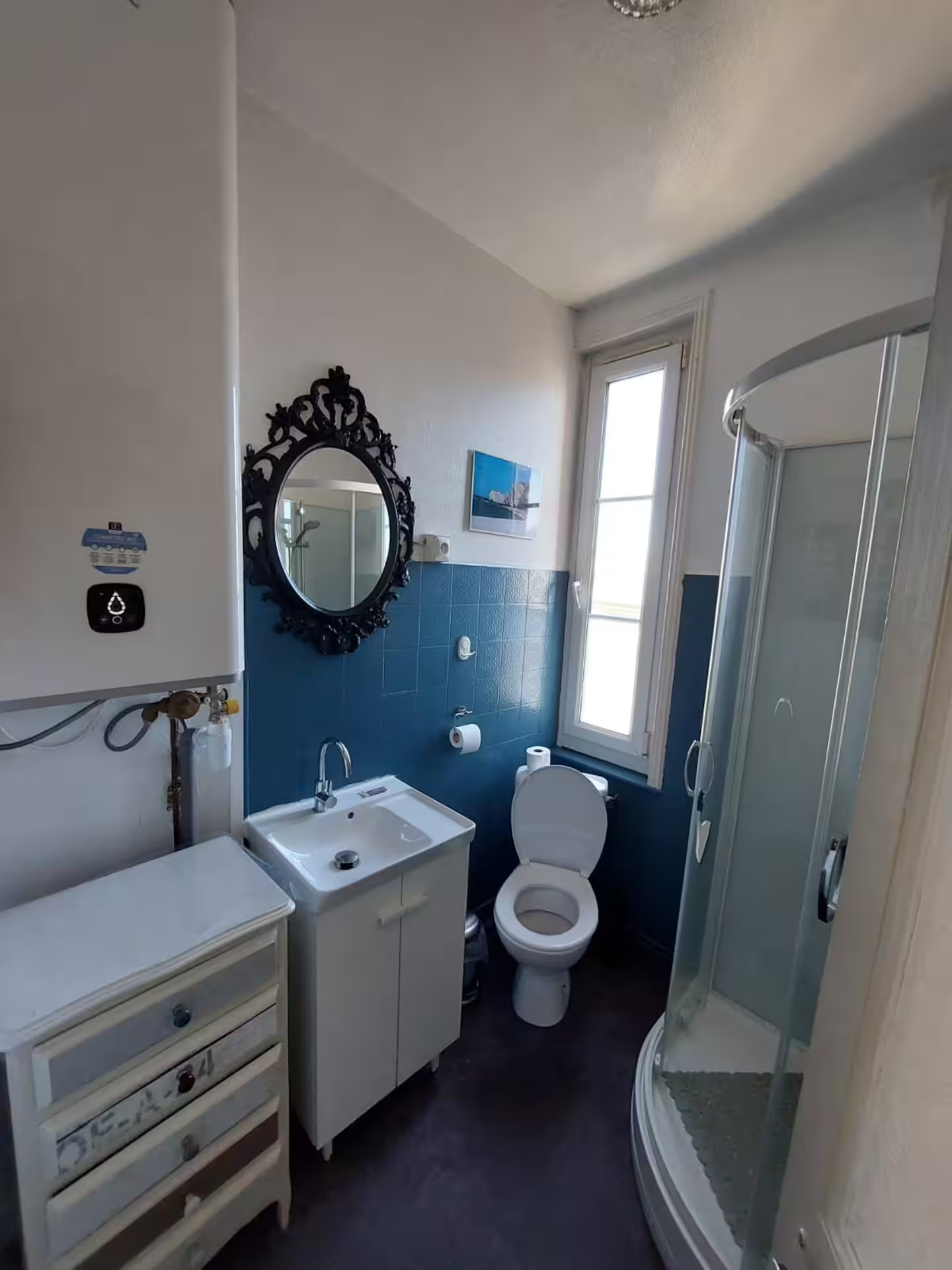 Une salle de bain avec WC, lavabo, miroir et douche.