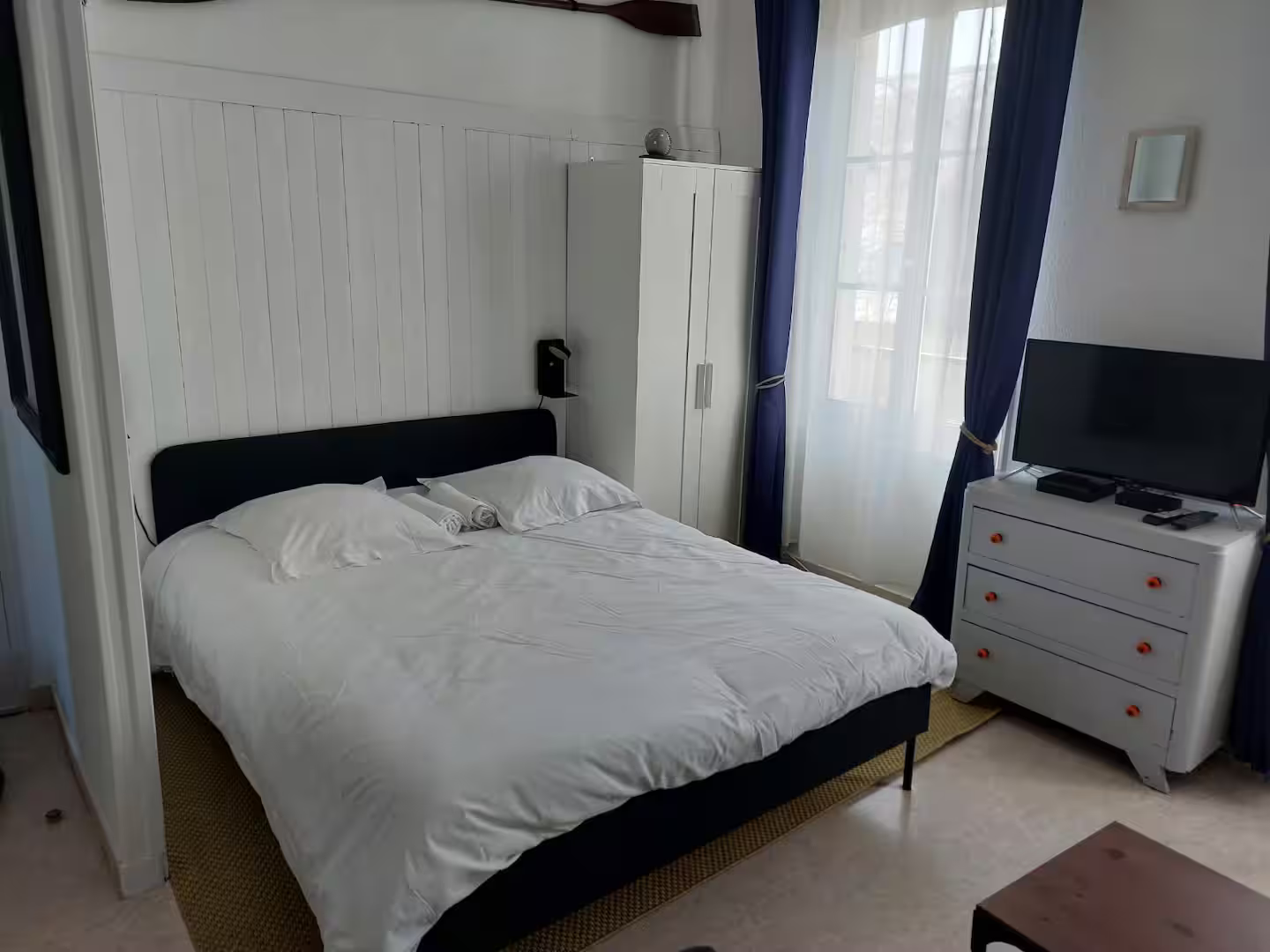 Une chambre avec un lit, une commode et une télévision.