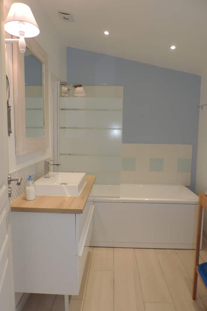 Salle de bains moderne avec meuble-lavabo blanc, baignoire et mur bleu clair.