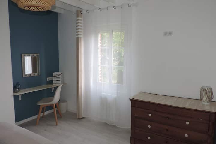 Intérieur d'une chambre avec un bureau, une commode, une fenêtre et un mur d'accent bleu.