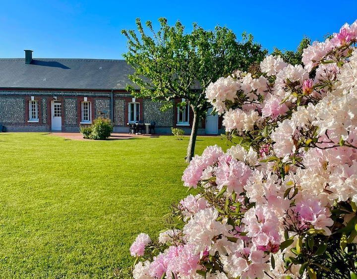 Jolie maison pour le gite la longère au puits au Tilleul proche d'Etretat vue d'extérieur avec des fleurs et un joli terrain avec ses arbres.