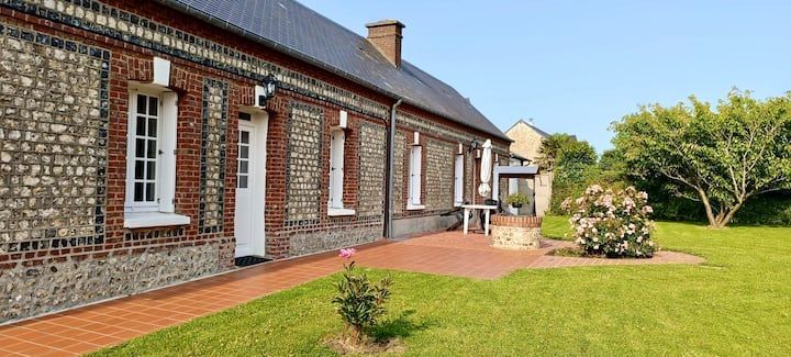 Maisonnette en briques avec pelouse verte et arbres.