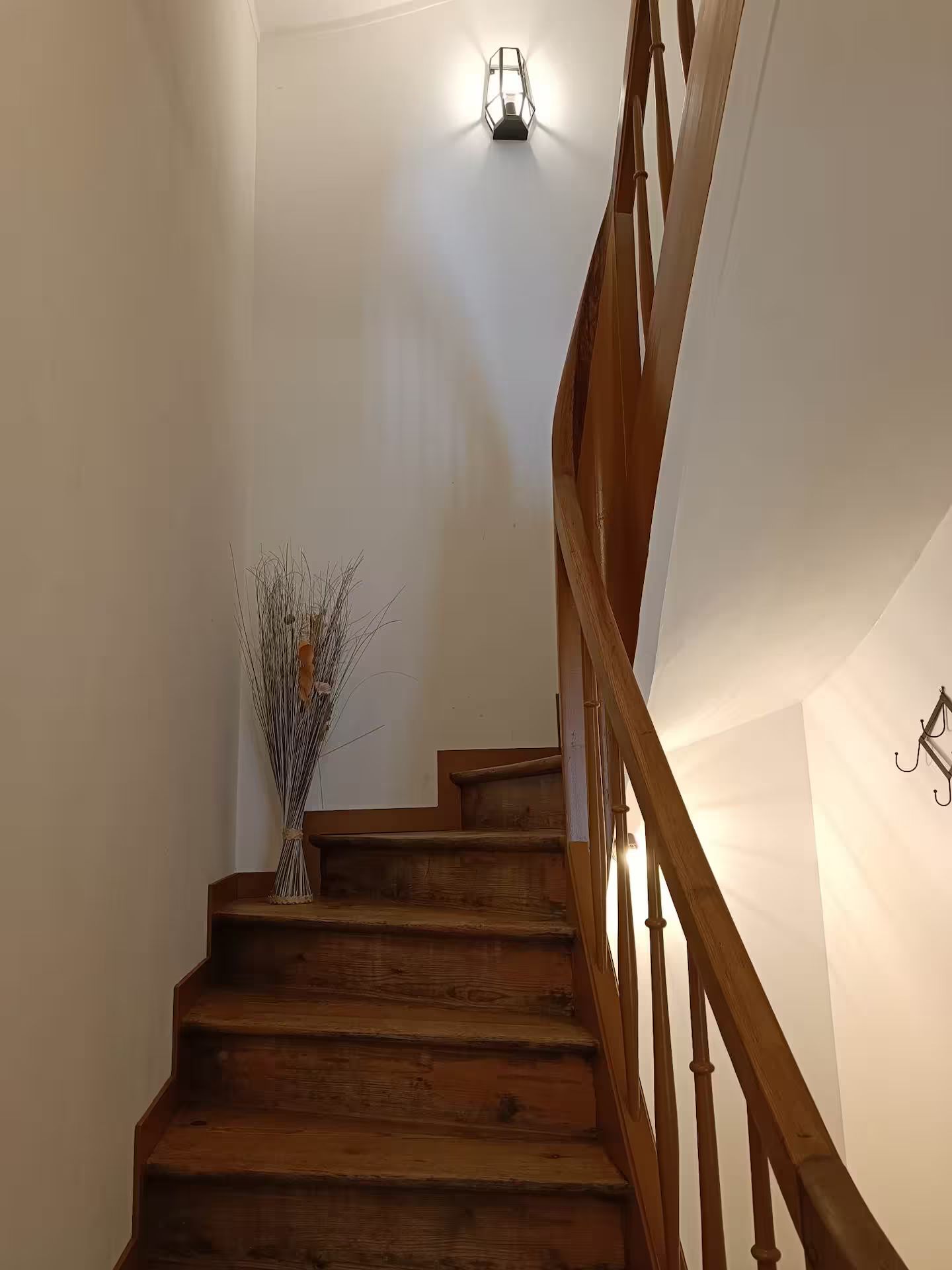 Un escalier en bois avec un vase de fleurs sur la marche inférieure