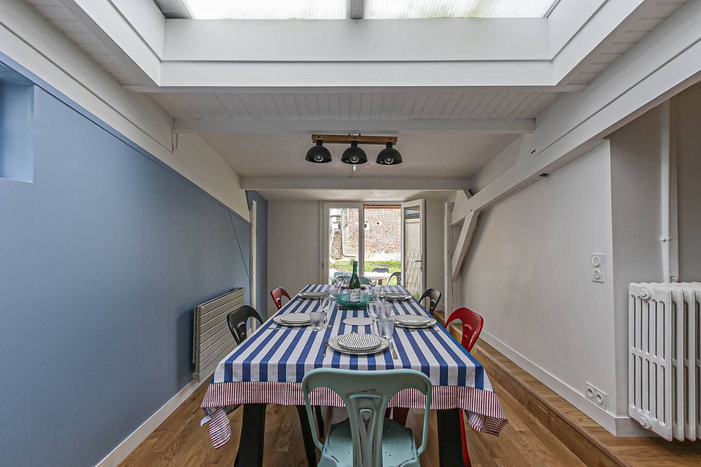 Une longue table de salle à manger avec une nappe rayée et des chaises.