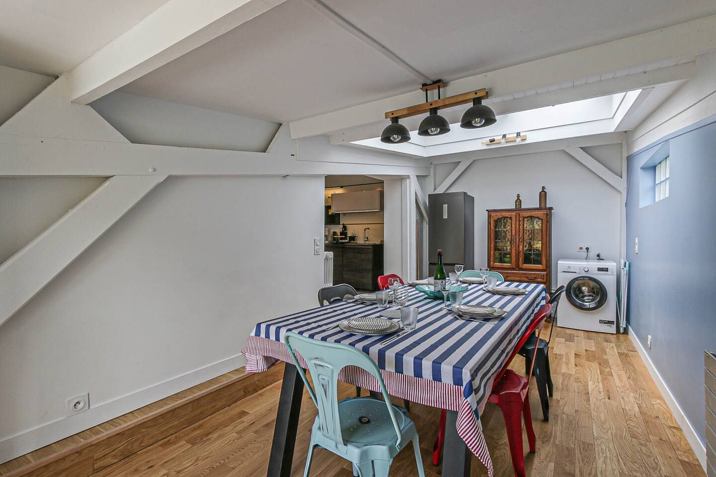Une salle à manger avec une table et des chaises ainsi qu'une laveuse et une sécheuse.