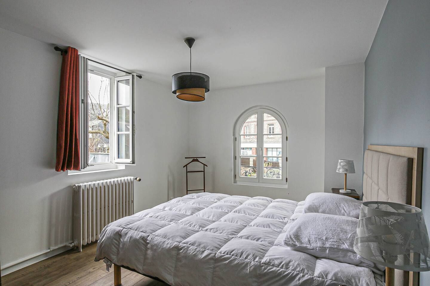 Une chambre avec un lit, une fenêtre, un radiateur et une lampe.