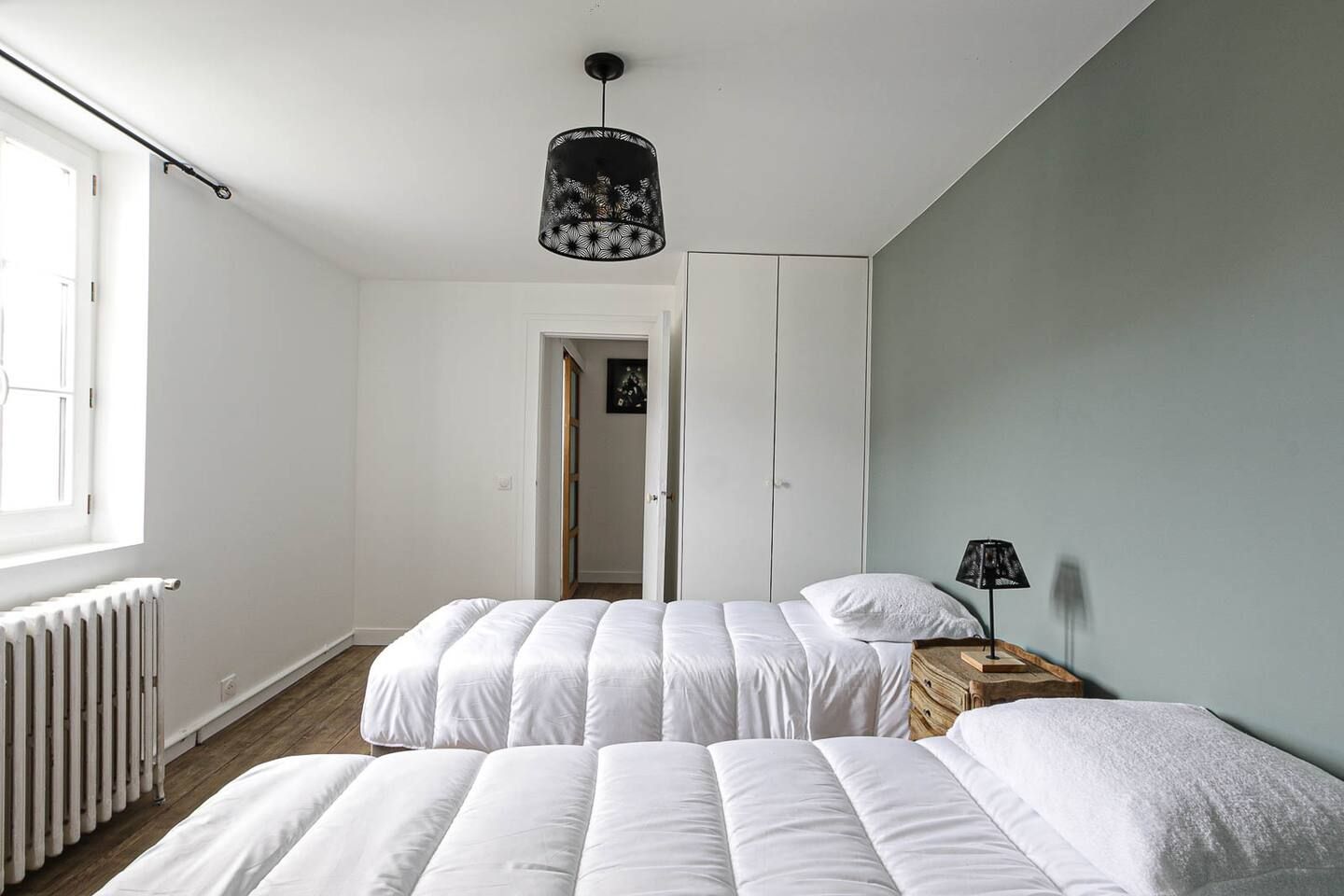 Une chambre avec deux lits et un radiateur.
