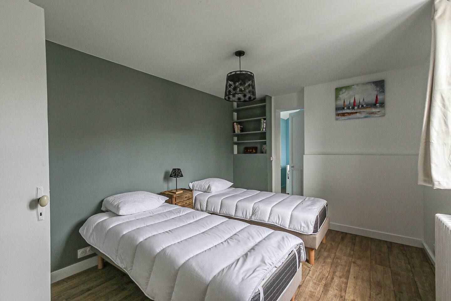 Une chambre avec deux lits et un tableau au mur.