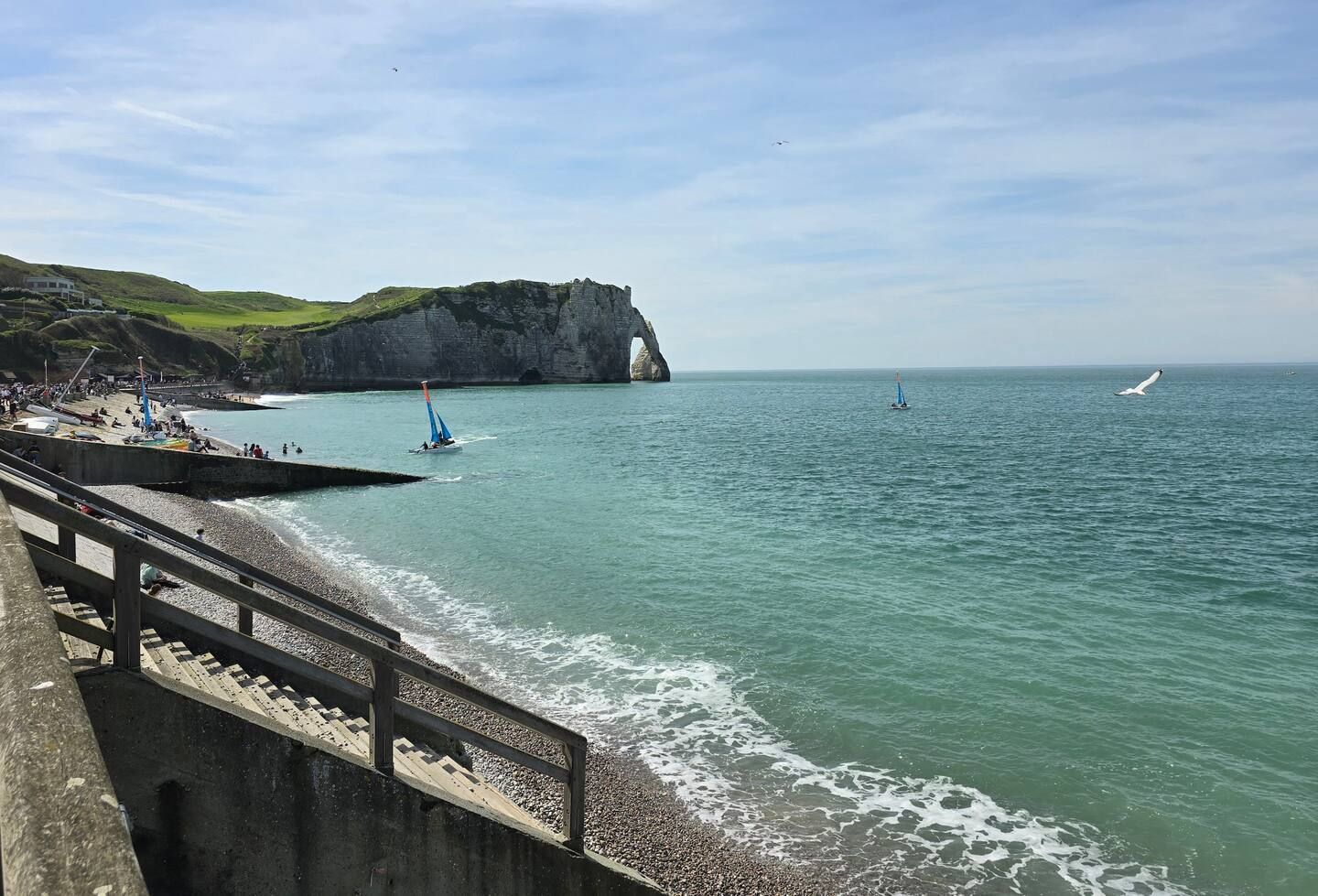 Une plage avec une falaise en arrière-plan et un bateau dans l'eau.