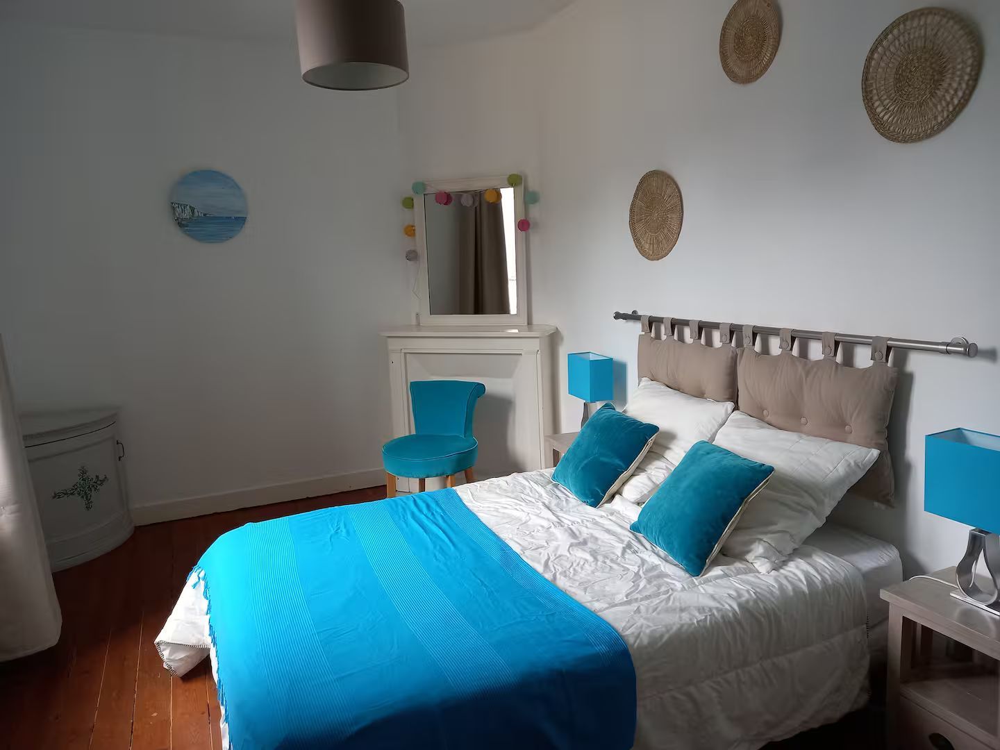 Une chambre avec un lit, une chaise, des lampes et un miroir.