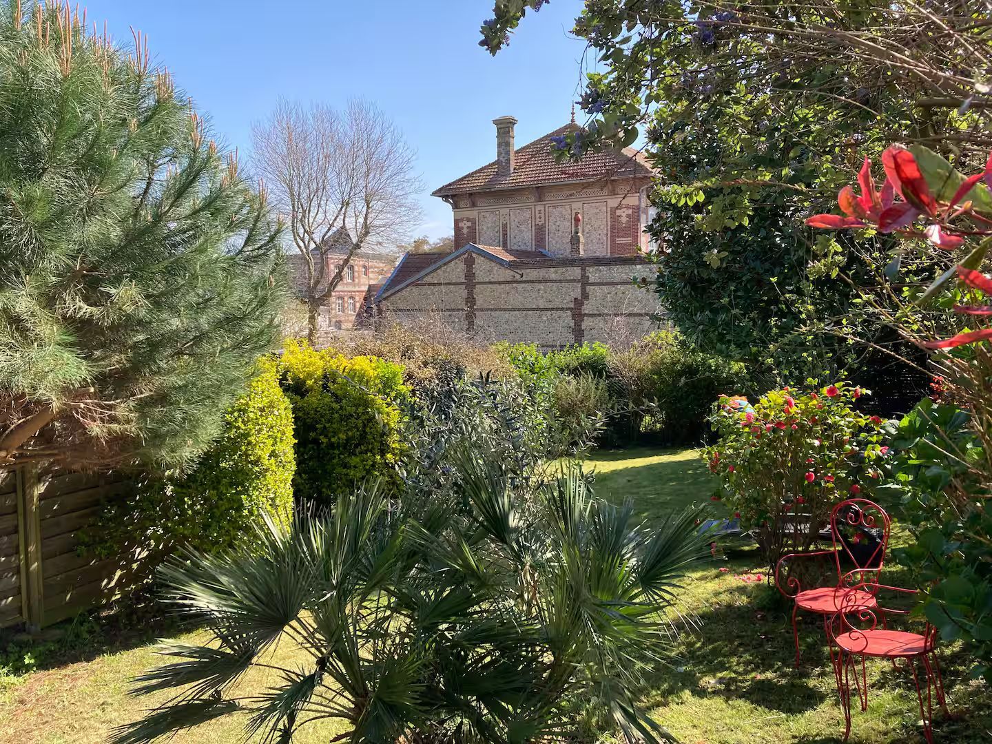 Une grande maison est entourée d'un jardin verdoyant.