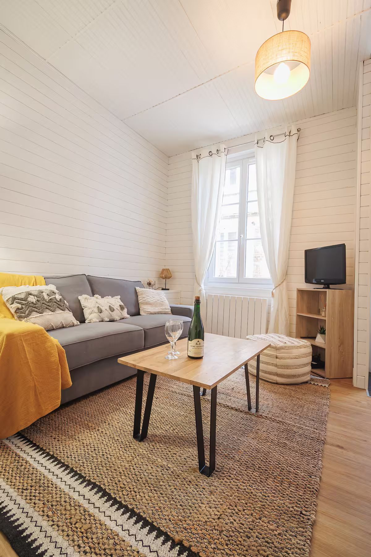 Un salon avec un canapé, une table basse et une télévision.