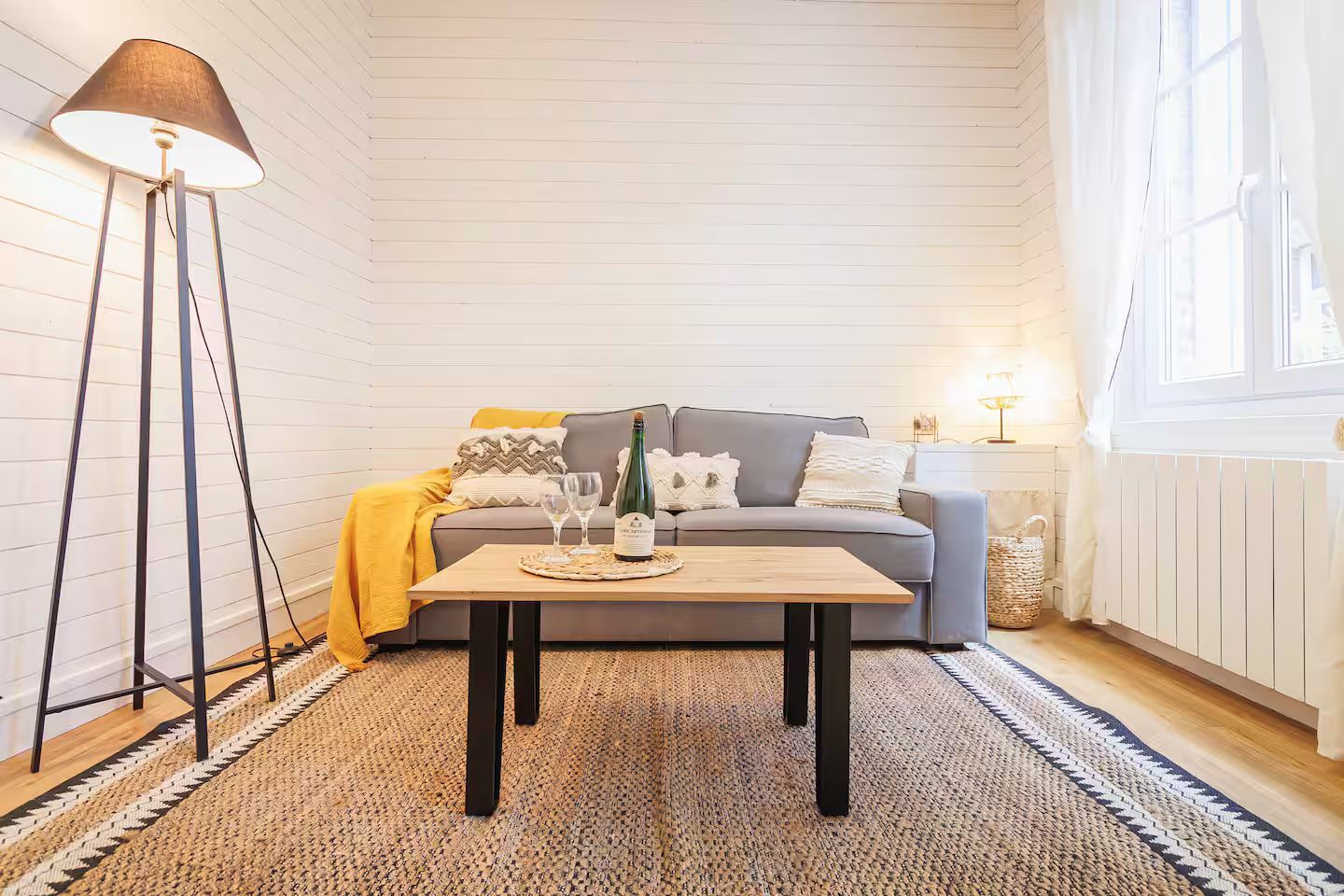 Un salon avec un canapé, une table basse, une lampe et un tapis.