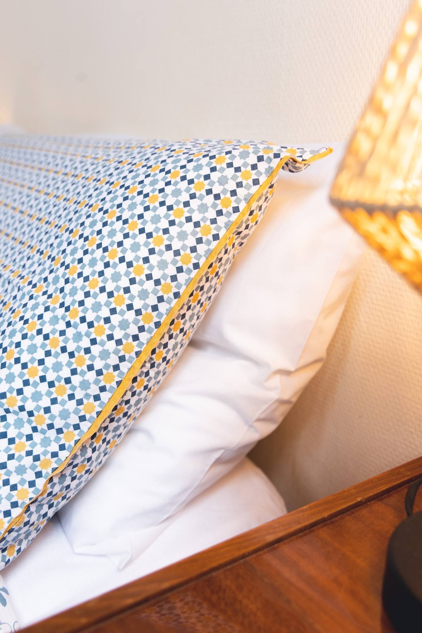 Un lit avec une couverture et des oreillers dessus à côté d'une lampe.