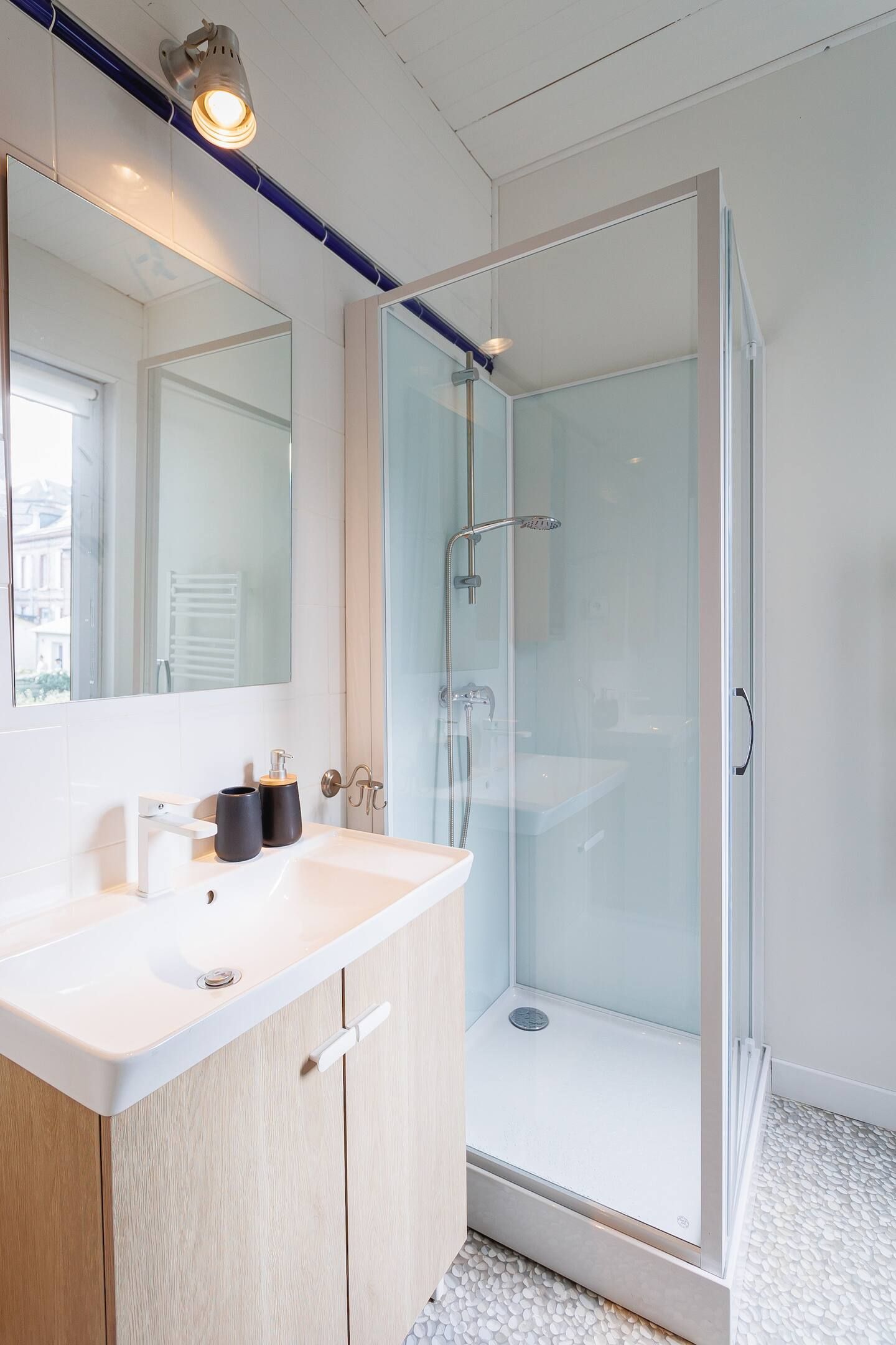 Une salle de bain avec lavabo, miroir et douche à l'italienne.