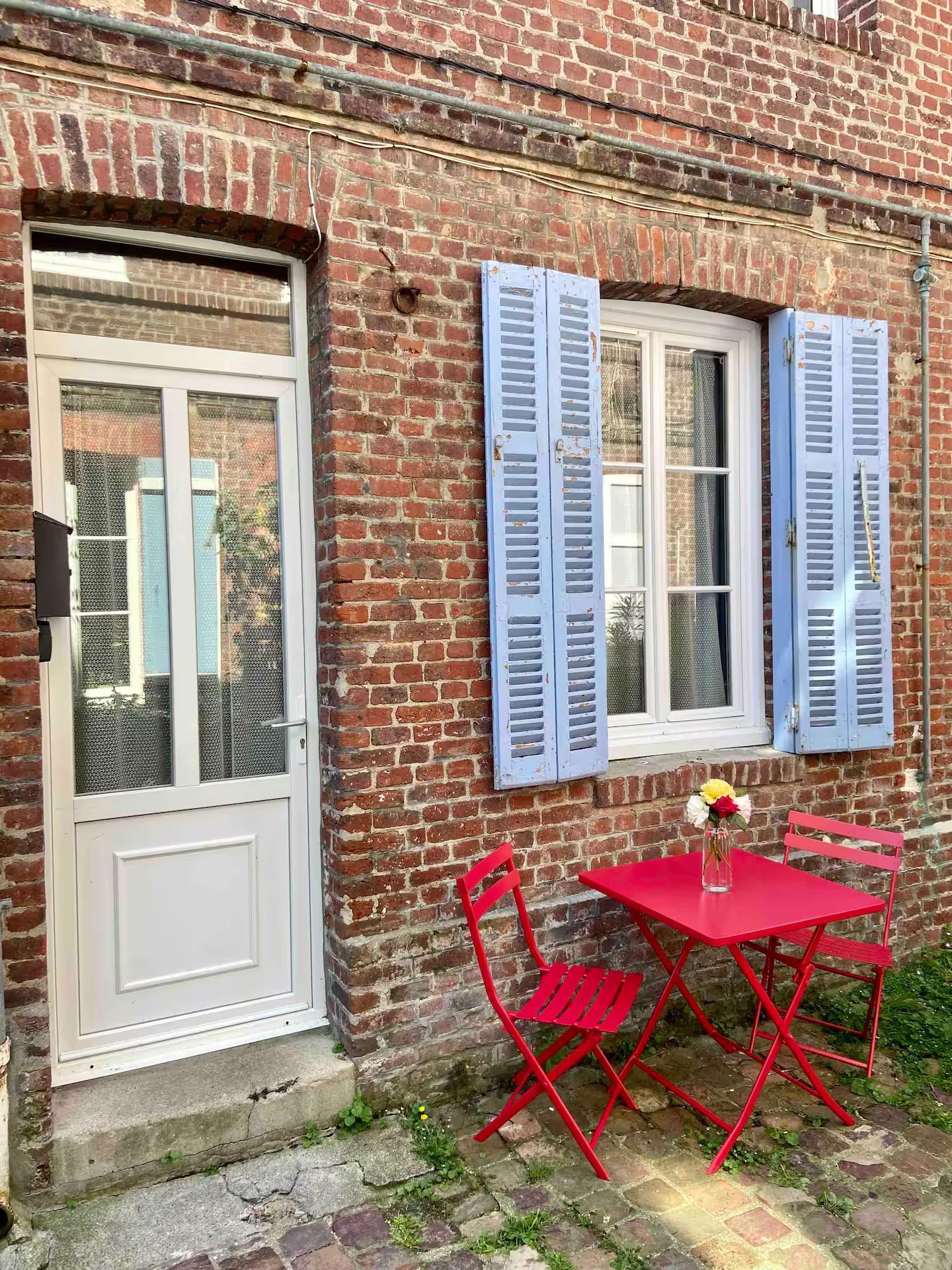 Il y a une table et des chaises devant un bâtiment en briques.