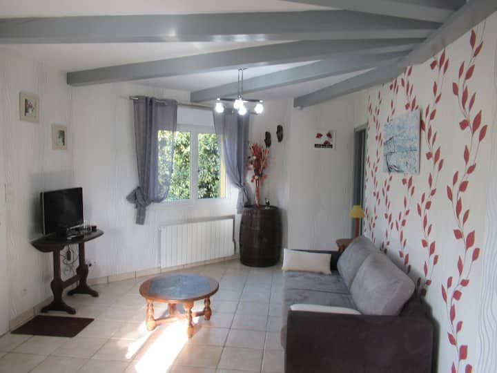 Salon avec poutres apparentes grises au plafond, fenêtre avec rideaux, murs blancs et mur d'accent à motifs floraux.
