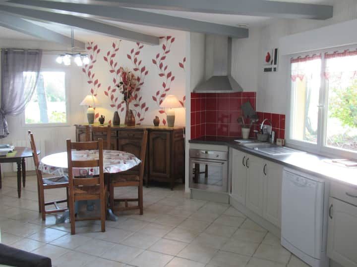 Cuisine et salle à manger à aire ouverte avec armoires blanches, table ronde et mur d'accent rouge.
